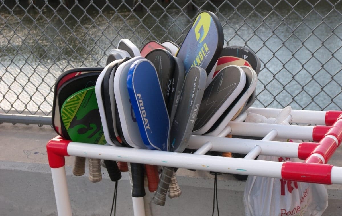 A large group of pickleball paddles on a rack